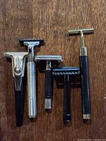 Five assorted vintage safety razors lined on wood surface