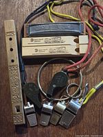 Group view of all whistles, harmonica, flute and lanyards