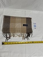 Folded scarf showing fringe and measuring tape for scale