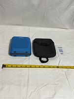 Top view of blue Bose SoundLink Color speaker next to grey cloth pouch with tape measure for scale