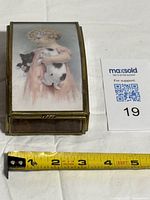 Closed brass mirrored music box with girl and kittens image, tape measure shows size