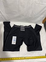 Full view of black Bracelayer compression pants laid flat with size tag visible