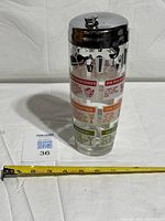 Full view of glass shaker with chrome lid and printed recipes, tape measure for scale