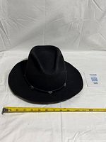 Front/top view of black felt Harley Davidson hat with measuring tape across brim