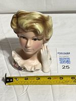 Front view of porcelain lady head vase with measuring tape for scale