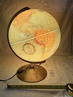 Globe lit showing South America and Africa, diameter tape for scale
