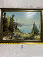 Full view of framed landscape painting with measuring tape showing width
