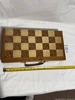 Closed folding board showing chess side and handle, tape for length