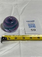 Paperweight beside tape measure showing diameter around 2.5 inches