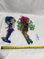 Both dolls laid flat with measuring tape for scale