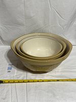 Four nested stoneware mixing bowls with measuring tape for scale