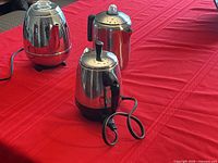 Three percolators on red cloth: GE pot-belly, Farberware electric, Copco stovetop