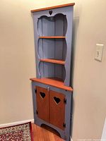 Full view of blue and cherry corner cabinet showing overall design and proportions