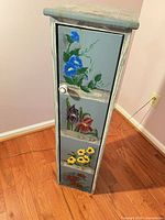Full view of cabinet closed showing floral artwork and knob