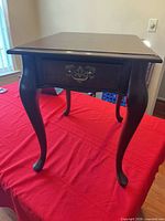 Overall view of wooden end table front showing drawer and legs
