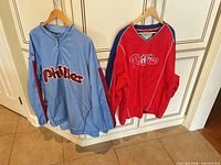 Both Phillies pullovers hanging to show full fronts