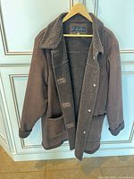 Full view of brown sherpa-lined coat on hanger