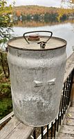 Side view of cylindrical galvanized oil can with bail handle