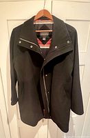 Full view of black Pendleton coat on hanger showing exterior front, zipper and snaps