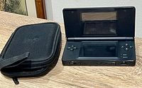 Front view of black Nintendo DS Lite console open alongside black zippered case