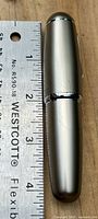 Closed pen beside ruler showing size