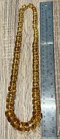 Full necklace beside 12-inch ruler showing length and graduated beads
