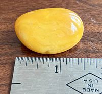 Top view of yellow Baltic amber cabochon brooch next to ruler showing size