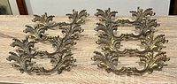 six brass drawer pulls arranged in two rows on wood surface