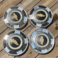 Four Chevrolet hubcaps laid out showing fronts