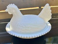 Side view of white milk glass hen on nest dish showing beaded rim and feather pattern