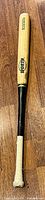 Full view of bat showing bamboo barrel, black handle, taped grip