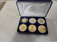 Blue presentation case open showing six encapsulated gold-tone coins