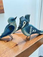 Three carved wooden birds on shelf, showing sizes and paint