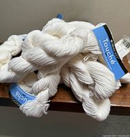 Pile of white skeins with Berroco Touche labels visible