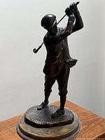Full view of golfer statue on wood base