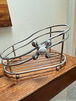 Full view of chrome metal bathroom caddy on wooden surface