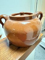 Full view of brown glazed bean pot with lid and handles