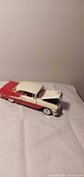 Full left side view of red and white 1955 Oldsmobile die-cast model