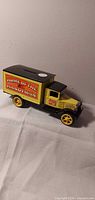 Full view of ERTL die-cast delivery truck coin bank, yellow and black, side shows wording