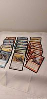 Three stacks of assorted Magic: The Gathering cards laid out on cloth surface