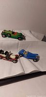 All three die-cast cars grouped on cloth backdrop