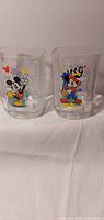 Two clear Mickey Mouse tumblers side by side