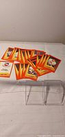 Spread of orange bordered Peoria Rivermen cards and two clear plastic cases