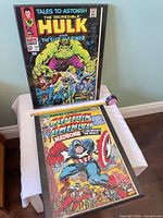 Both framed posters standing upright showing full covers