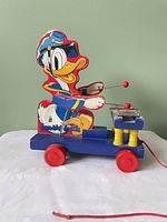 Left side view showing Donald Duck figure, mallets, metal keys, red wheels, pull cord