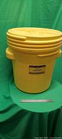 Front view of yellow 20-gallon bin with lid seated, ruler for scale