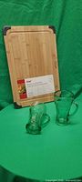 Two Coca-Cola glasses lying in front of sealed bamboo cutting board