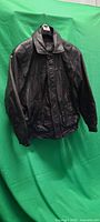 Front view of black leather jacket, shows zipper, snaps, pockets