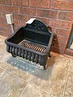 Full view of cast iron fireplace grate against brick wall