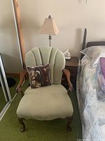 Front view of antique chair showing scalloped back, arms, legs and pillow